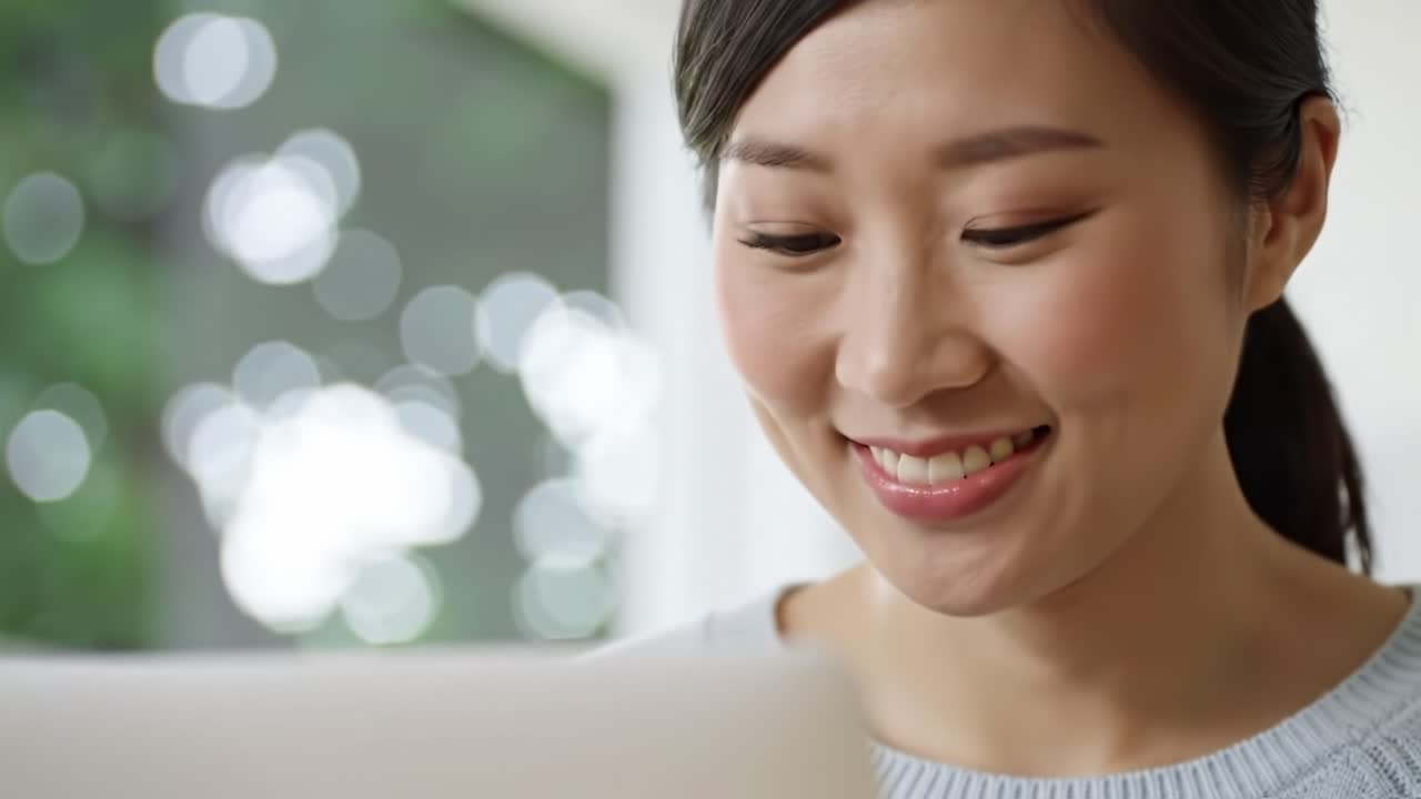 Captivating Moments of a Young Woman Engaged in a Lively Online Interaction While Smiling and Connecting Through Her Laptop in a Bright, Inviting Environment