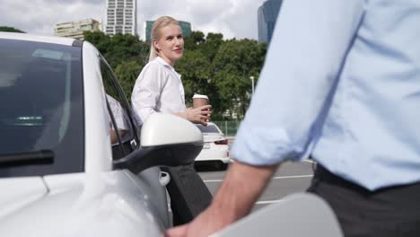 hombre de negocios y mujer de negocios progresistas apoyándose en el coche y el punto de carga.