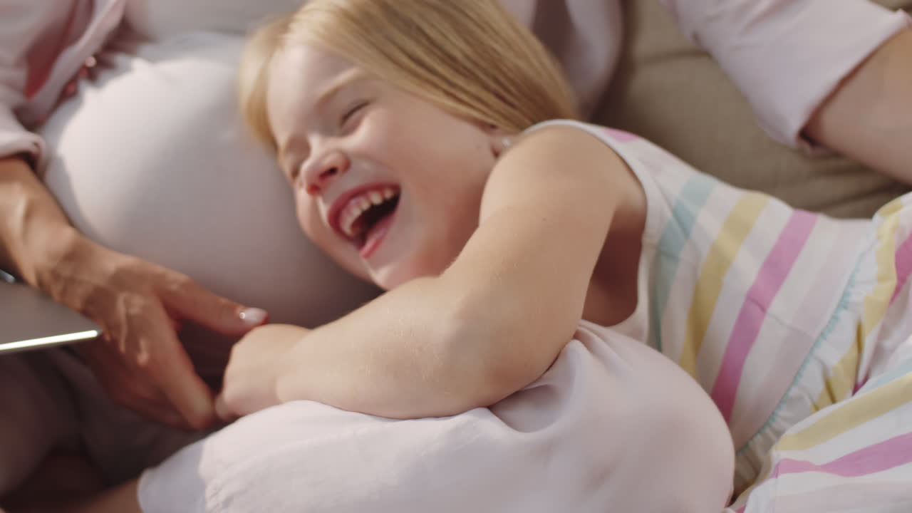 Bambina carina che abbraccia la mamma incinta e ride
