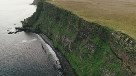 low flight along sheer, rugged cliff of grimsey island, iceland, arctic circle