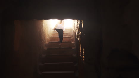 person descending stone stairs in an ancient cave