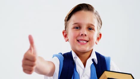 Smiling-schoolboy-with-books-showing-thumbs-up