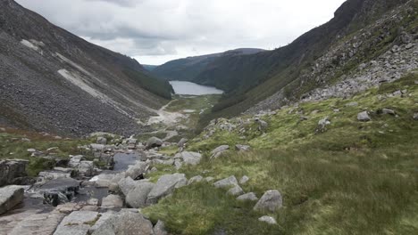 Agua-Que-Fluye-Hacia-Abajo-A-Través-De-Las-Rocas-Cerca-Del-Lago-Superior-Glendalough-En-El-Condado-De-Wicklow,-Irlanda---Drone-Aéreo