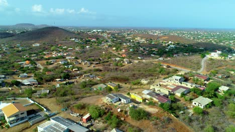 4k-drone-aerial-cinematic-of-neighborhoods-and-houses-in-an-urban-rural-area-of-the-Caribbean-island-of-Curacao,-curvy-landscape-filled-with-hills