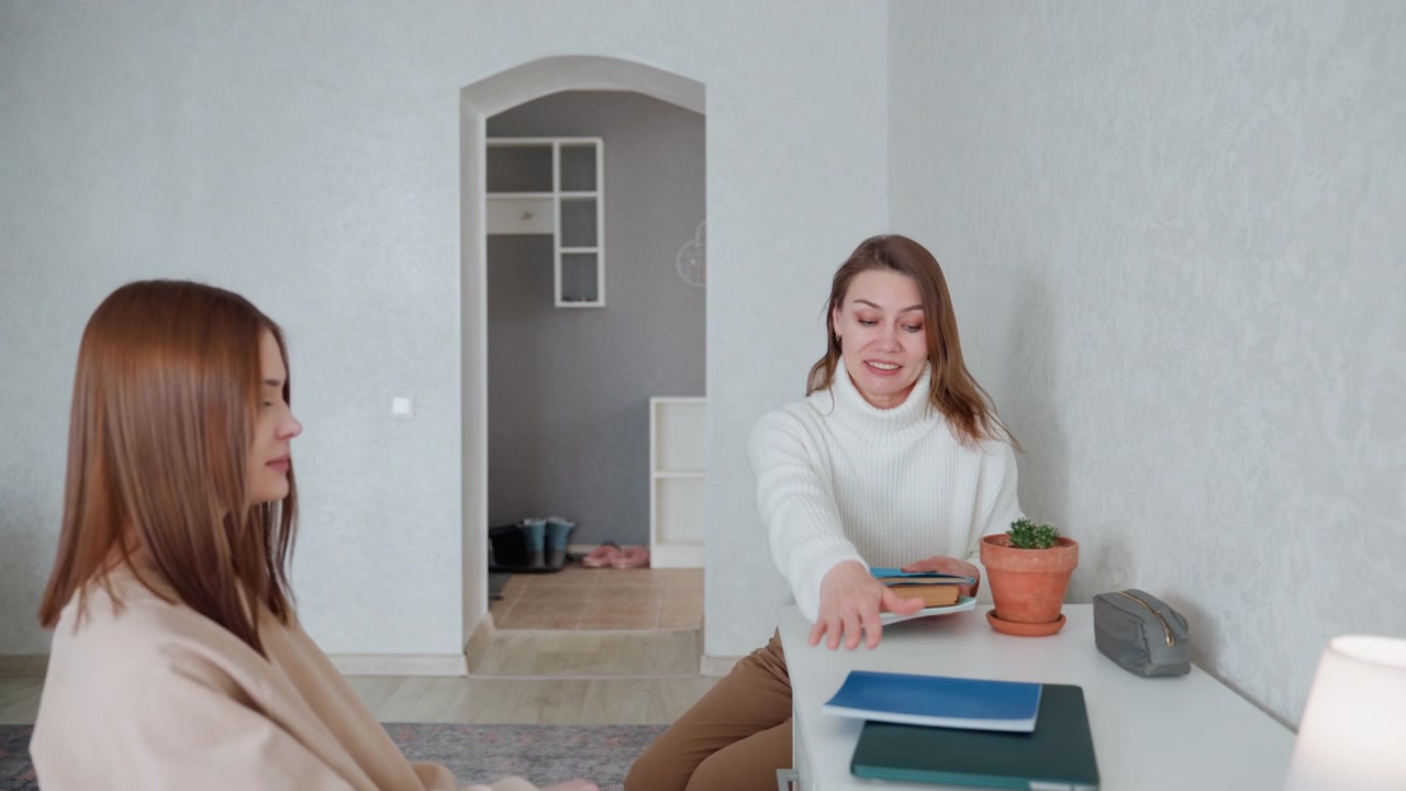 Treinador(a) recebendo estudante na entrada do quarto com livros, aperto de mão e risadas, prática colaborativa de gramática, mulher oferece livro de exercícios, estudante sorri e se junta à mesa, moderno e minimalista.