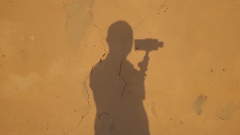 abstract view of shade man holding gimbal reflected on yellow cracked wall