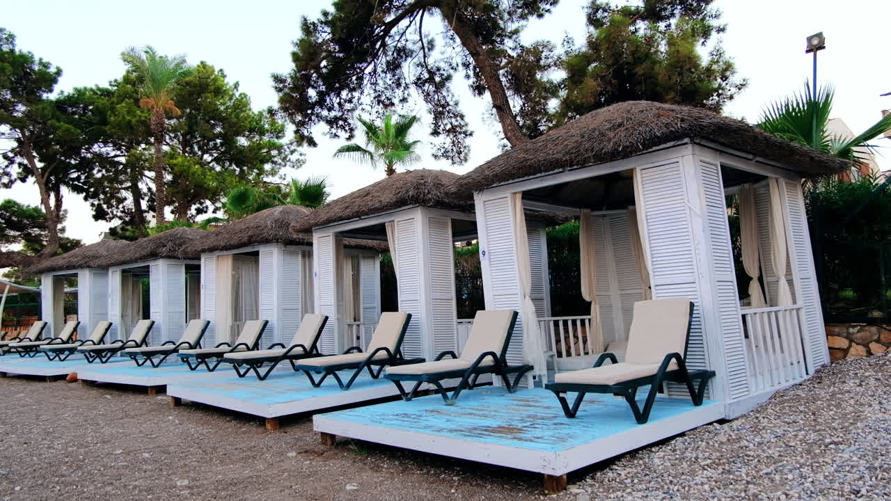 View of the beach at Mediterranean sea coast in Kemer at sunset, Turkey. Lots of sun beds and tents