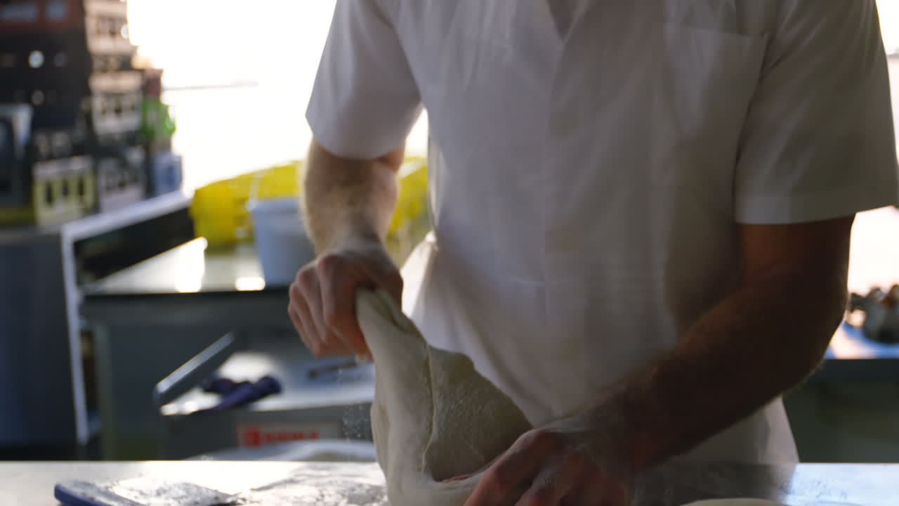 Male chef kneading the dough on worktop 4k