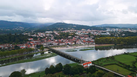 Stunning-aerial-4K-drone-footage-of-a-village---Ponte-de-Lima-in-Portugal-and-its-iconic-landmark---Stone-roman-bridge-crossing-over-the-Lima-River