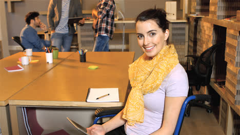 Female-business-executive-sitting-on-wheelchair-and-using-digital-tablet