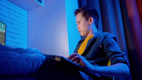 teenager playing video game on pc. boy plays computer games using keyboard while sitting at home. teens lifestyle and computer concept.