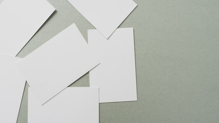 Multiple blank white business cards on green background, copy space, slow motion