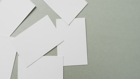 multiple blank white business cards on green background, copy space, slow motion