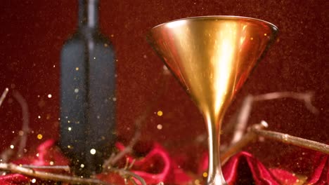 shimmering particles descend upon a golden glass and black bottle set against a crimson backdrop, embodying notions of opulence, festivity, celebration, and holiday cheer