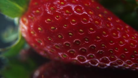 macro detailed video of a pile of strawberries, red strawberry, green fruit, tiny seeds, on a rotating reflection stand, smooth movement