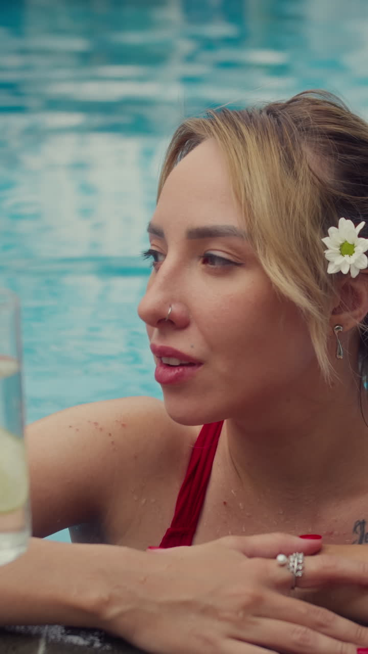 Jovem posando para a câmera enquanto nada na piscina em resort
