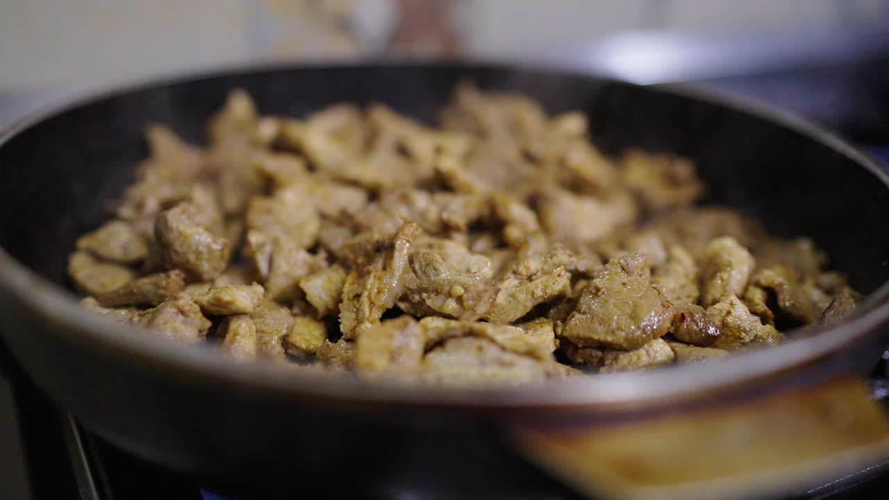 Sizzling pork cooks in a pan, a delicious ingredient for traditional Bagna Cauda sauce.