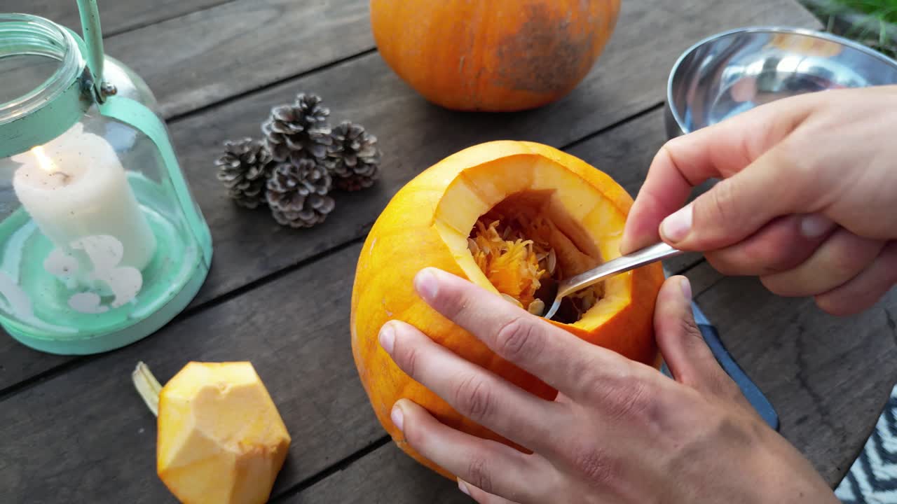 primer plano de manos masculinas ahuecando calabaza para el jack-o-lantern de halloween