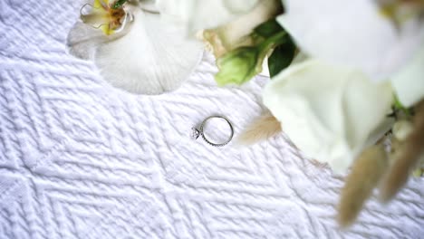 engagement ring and bouquet of flowers on bed - high angle