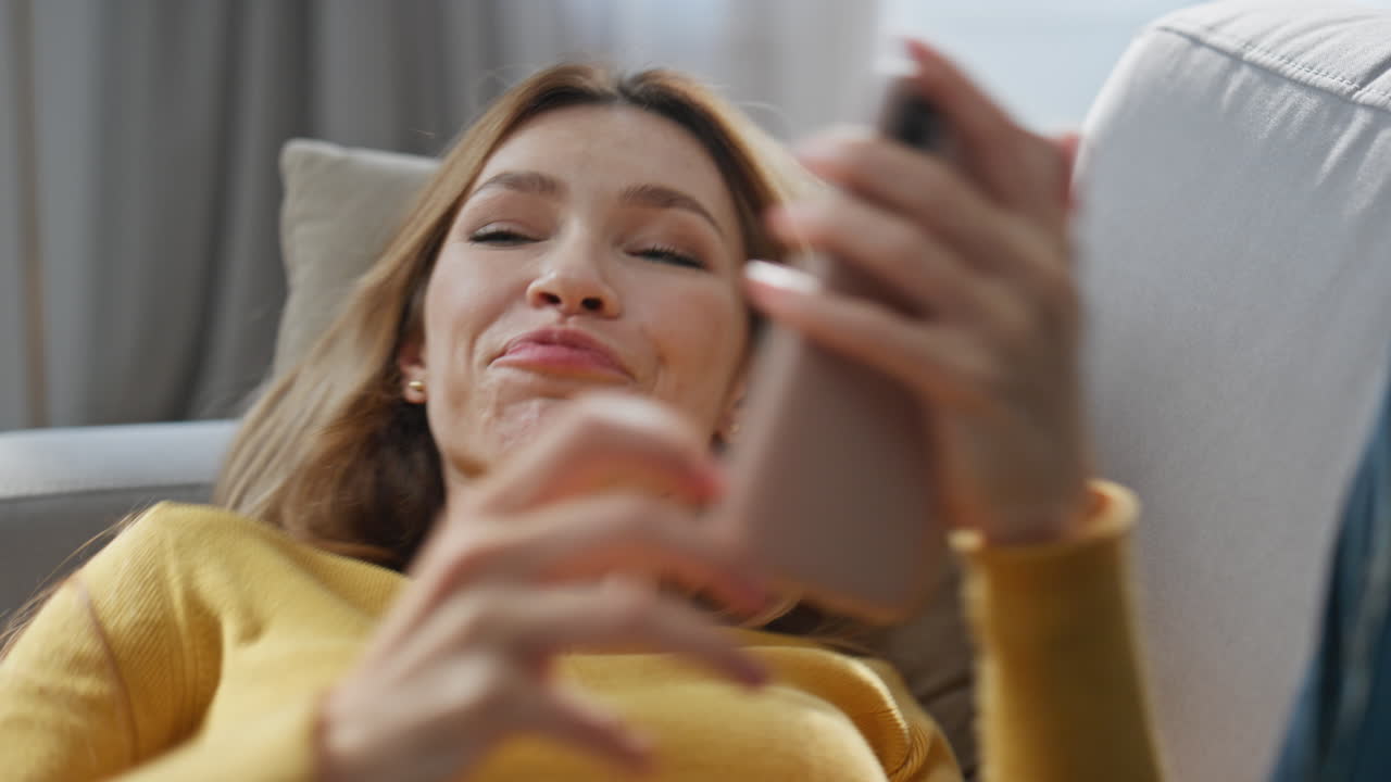 Romantic girl messaging boyfriend laying sofa closeup. Carefree woman chilling