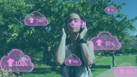 Animation-of-clouds-and-arrows-over-woman-listening-to-music-in-a-park