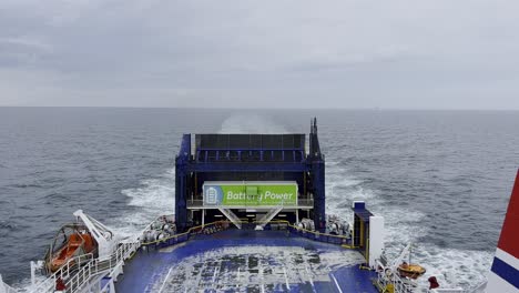 View-of-the-end-of-a-car-ferry-sailing-across-the-sea-under-an-overcast-sky,-blue-and-white-ship