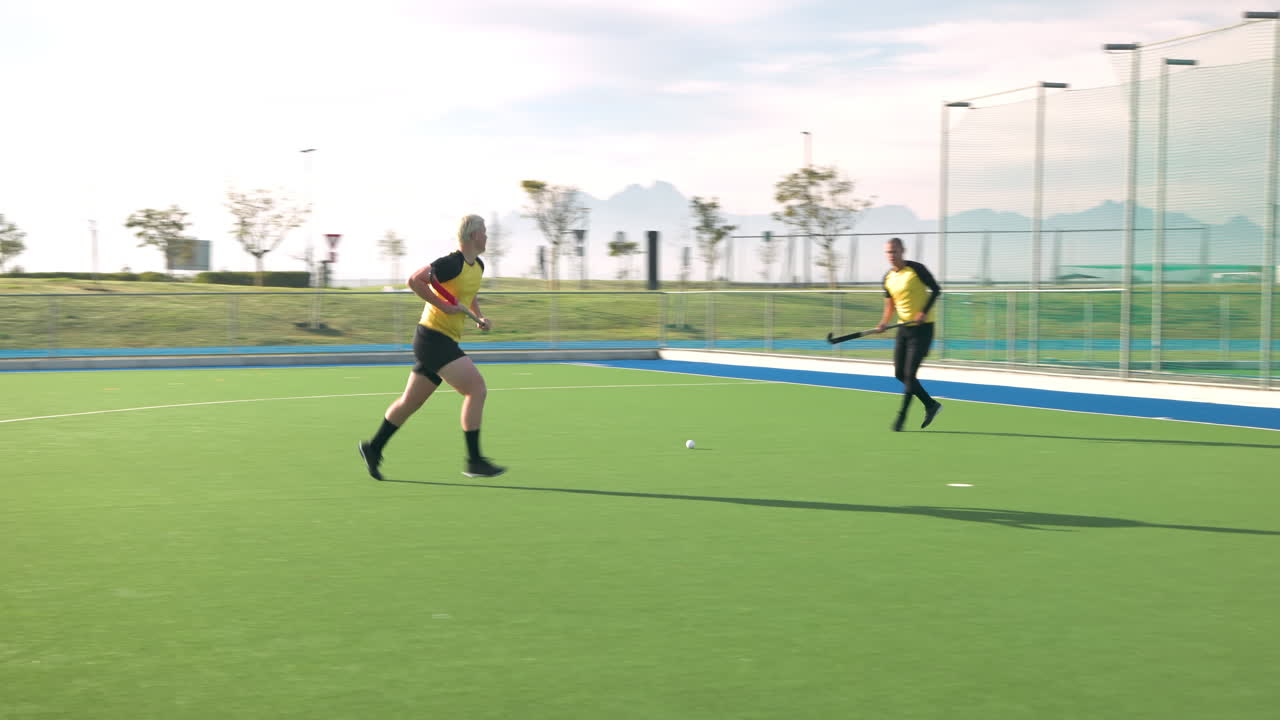 Playing field hockey, male player aiming to score against goalkeeper
