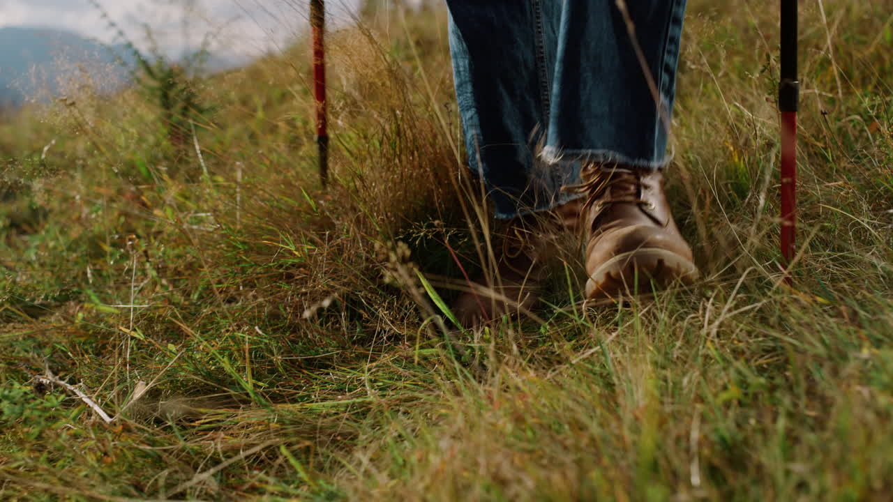 Nahaufnahme: Wanderschuhe und Beine beim Trekking in der Bergwelt. Tourist geht einen Hügel hinauf.