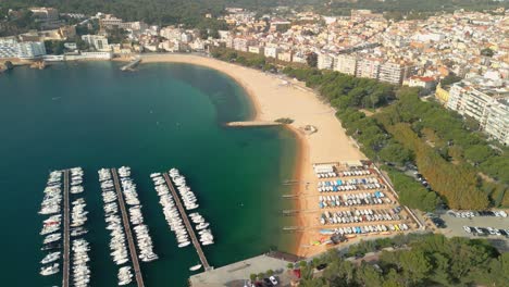 imágenes aéreas de sant feliu de guixols en la costa brava de girona pequeñas embarcaciones en la playa de arena amarilla y agua azul turquesa del mediterráneo