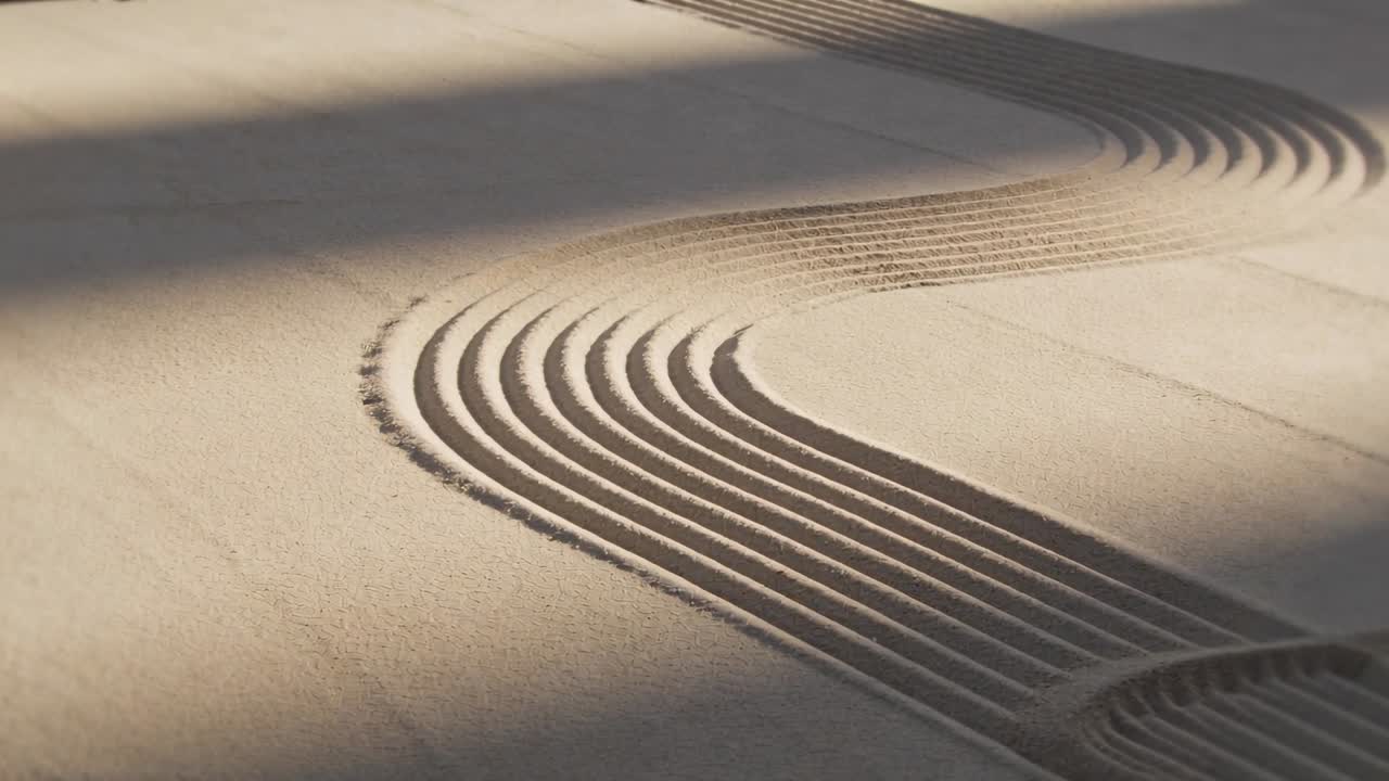 Panning camera revealing sand bed raked S-shaped grooves on tray, showing ridges, shadows for calm