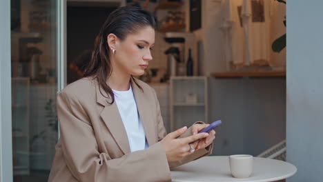dama rica con aspecto de teléfono inteligente en un café al aire libre de cerca. mujer de negocios seria