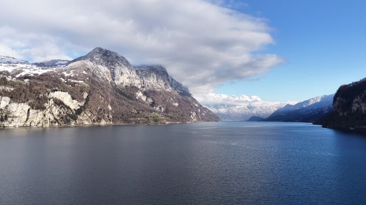 Aerial view of Walensee Lake in Switzerland, surrounded by alpine mountains and calm blue water, capturing wide natural scenery, peaceful atmosphere, and dramatic Swiss landscape from above