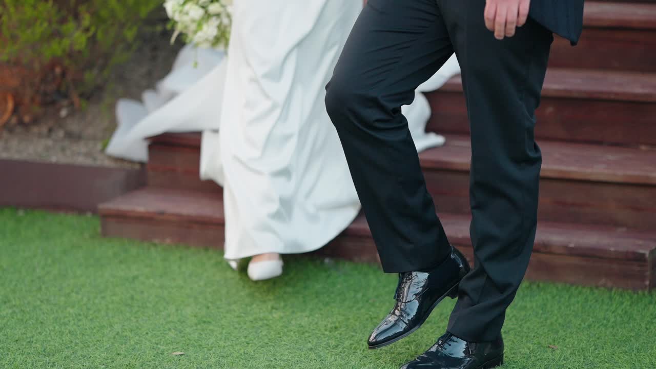 close up of bride and groom descending steps outdoors holding hands with bouquet