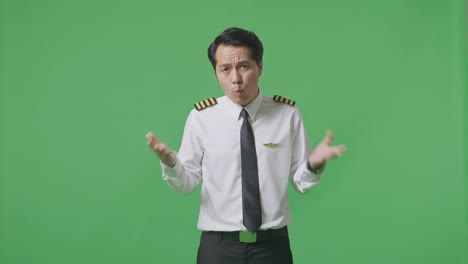 wondering asian man pilot saying why and standing doubtfully in the green screen background studio