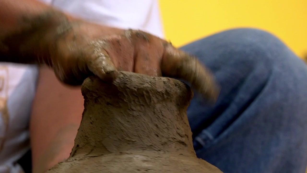 Vista ravvicinata di un vasaio che modella un vaso di argilla a mano durante un tradizionale processo artigianale di ceramica con texture umida, abilità artistica e lavoro di ceramica fatto a mano