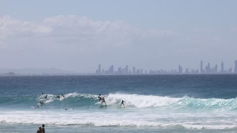 surfers ride waves with distant city skyline backdrop