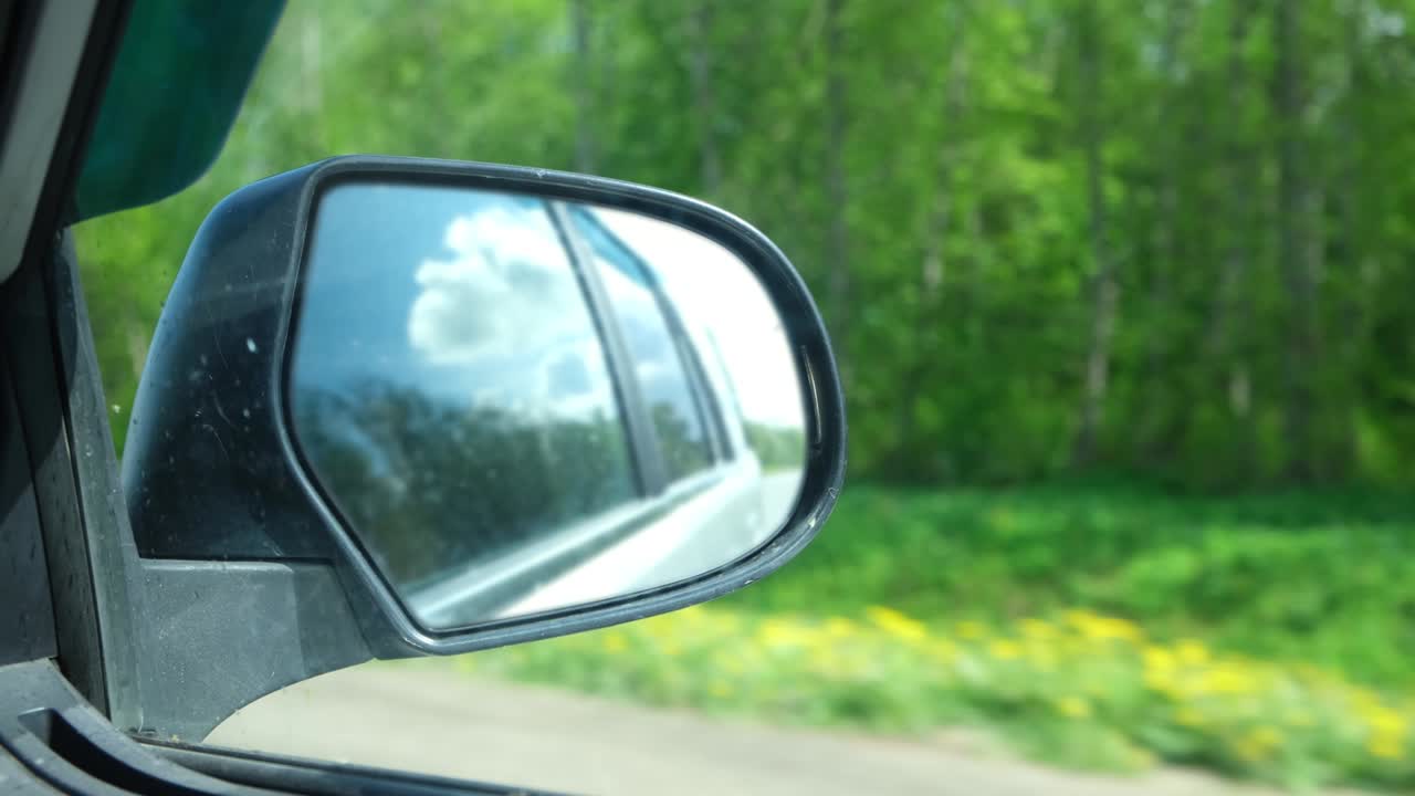 espejo de vista lateral reflejo de automóvil en movimiento en la carretera. carretera a lo largo de bosque verde y árboles en verano. turismo y viajes, concepto de viaje de viaje. hermosa naturaleza y paisaje. carretera de velocidad de automóvil.