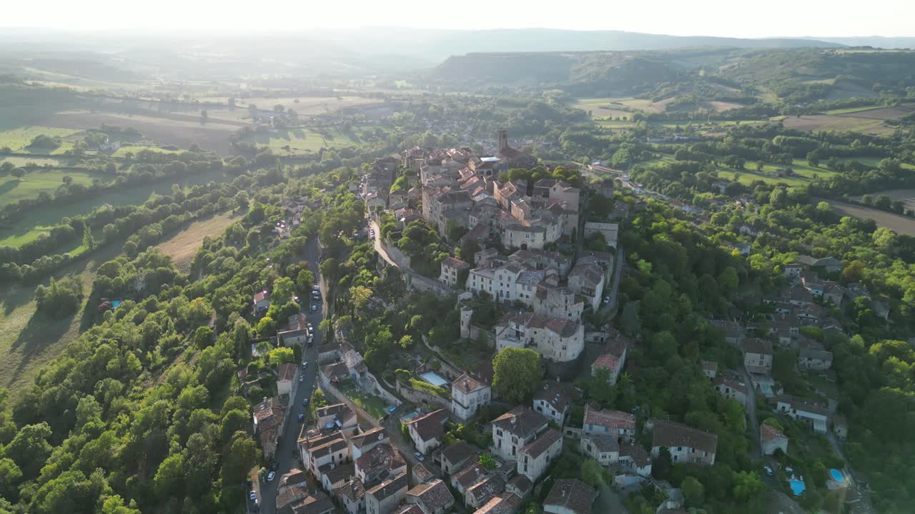 Drone aerial view in France countryside small old medieval brick town on a mountain top surrounded by green fields slight move on a sunny day in Cordes Sur Ciel