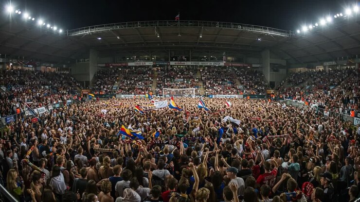 Un mare di entusiasmo: una folla di tifosi che festeggia in uno stadio affollato con bandiere e piena energia durante il culmine emozionante di un evento sportivo