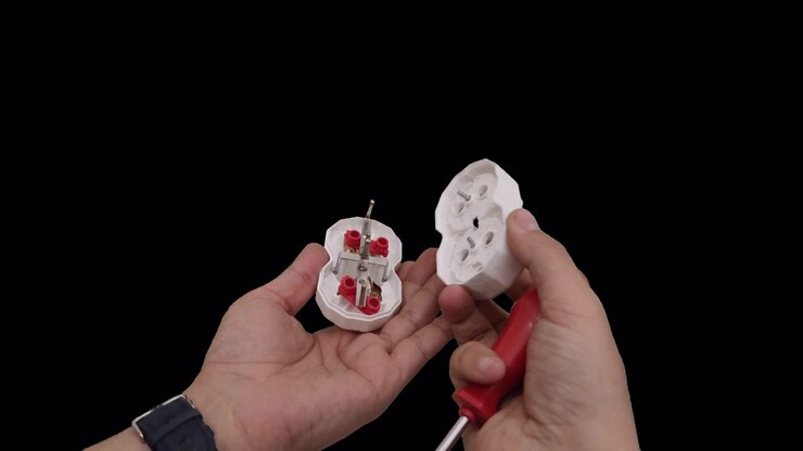 Person Disassembling a White Electrical Socket with a Screwdriver