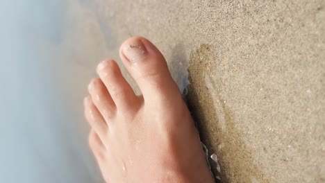 Gold-glittered-pedicured-foot-spreading-toes-in-the-clean-ocean-waves