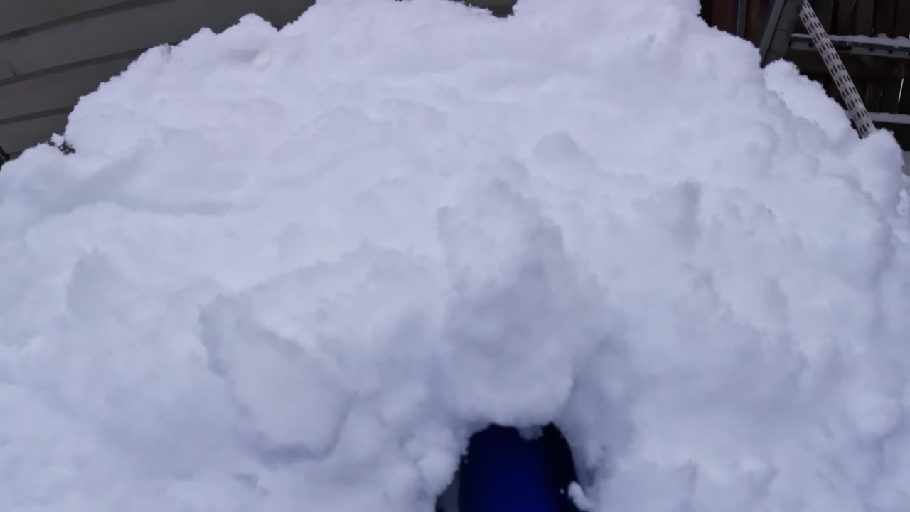 First person view pushing blue shovel to clear snow from icy sidewalk in winter weather
