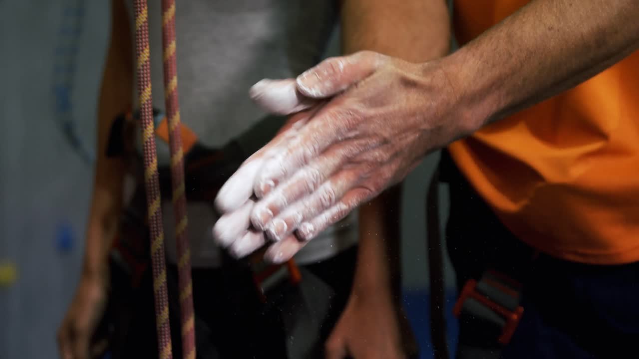 hombre frotando sus manos con polvo de tiza en el gimnasio de bouldering 4k
