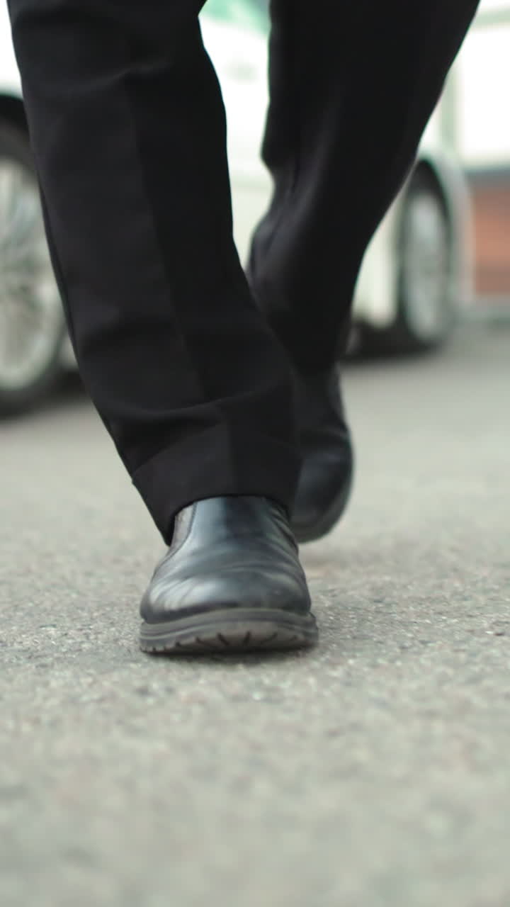 vista de cerca de la pierna de un individuo caminando al aire libre, con el fondo con un coche blanco estacionado y un edificio, pasos en el entorno urbano, destacando el paseo casual cerca del vehículo