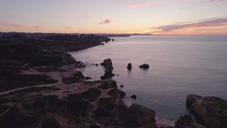 Side-panning-shot-of-Praia-dos-Arrifes-amazing-coastline-Portugal,-aerial