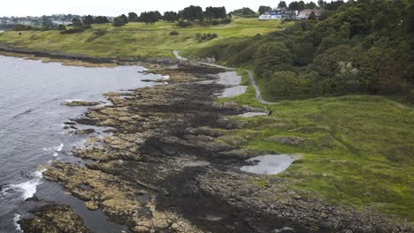 Panning-aerial-looking-down-rocky-coastline-in-Crawfordsburn,-County-Down