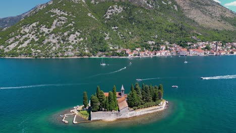 aerial drone view of sveti dorde island - saint george monastery in the middle of the island. in background is perast city. famous travel destination in montenegro. drone forward, descending.