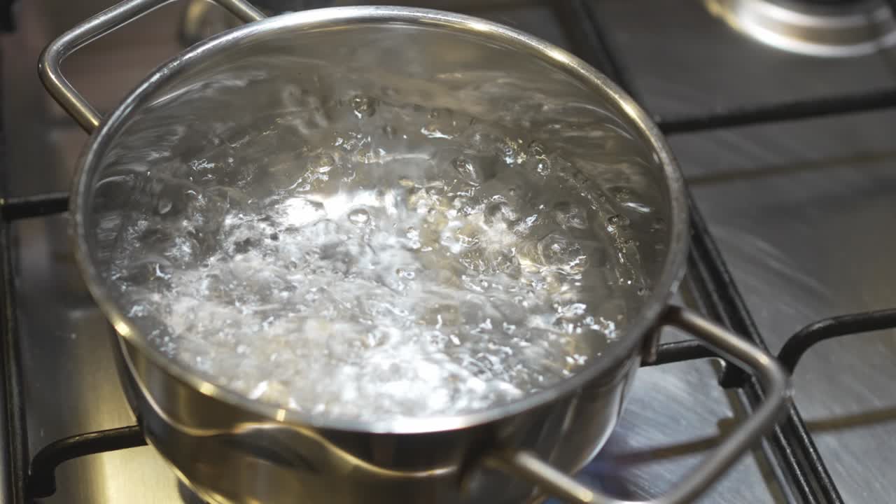 water boils in a saucepan on the burner of the gas stove.