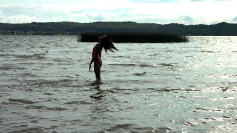 Silueta-De-Mujer-Arrojando-Sus-Propios-Pelos-Al-Aire-En-El-Océano,-Tiro-A-Cámara-Lenta