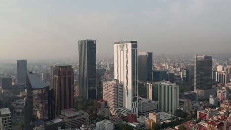 Tiro-Panorámico-De-La-Curva-Del-Centro-De-La-Ciudad.-Volando-Hacia-Altos-Edificios-De-Oficinas.-Visibilidad-Limitada-Debido-A-La-Contaminación-Del-Aire.-Ciudad-De-México,-México.